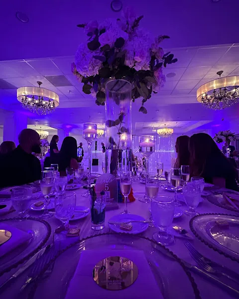 A table glowing in amethyst light beneath a tall floral centerpiece.