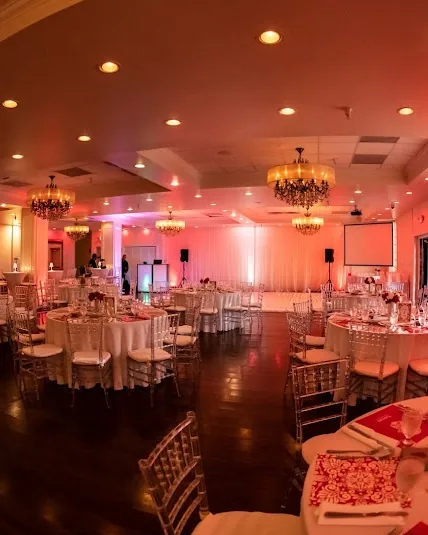 The hall in coral light, set with round tables and chandeliers.