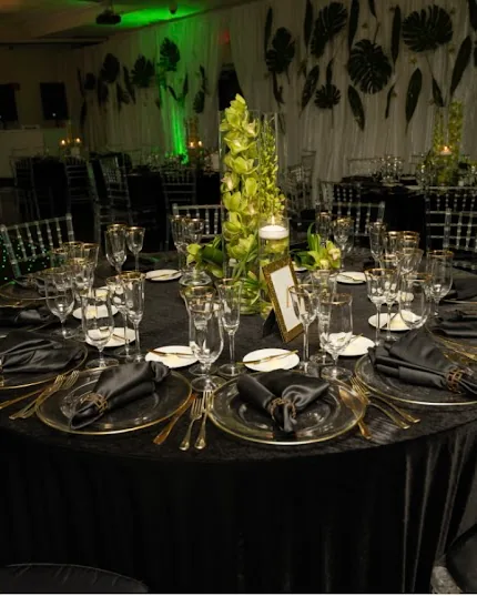A black-dressed table with orchids under emerald light.