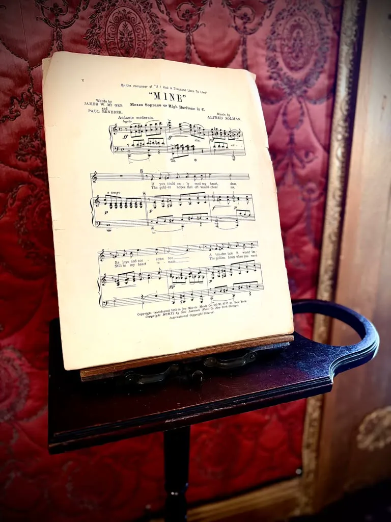 An open music score against patterned red wallpaper inside the house.