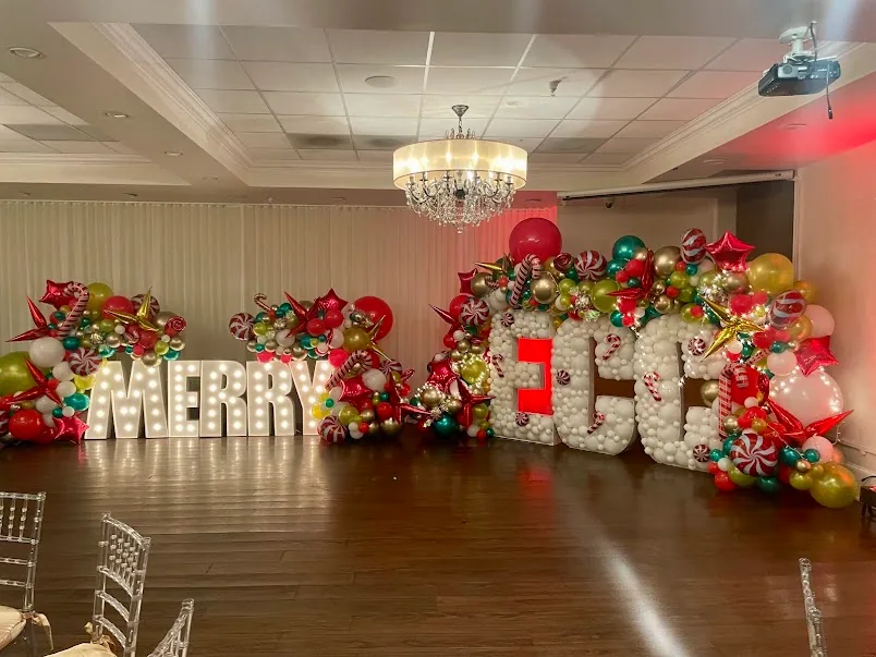 The hall dressed for a holiday party with balloon garlands and marquee letters.