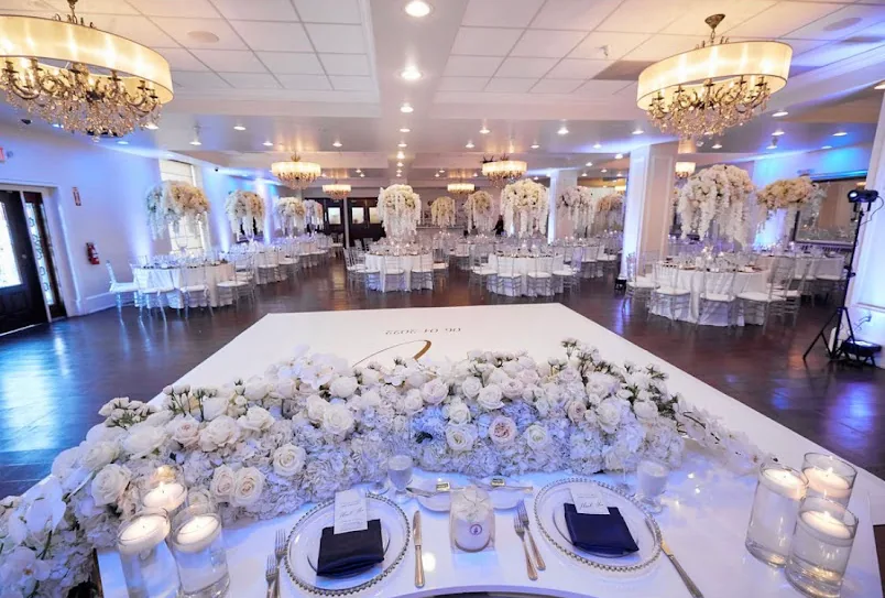 A head table dressed in white flowers and candles on a monogrammed dance floor.