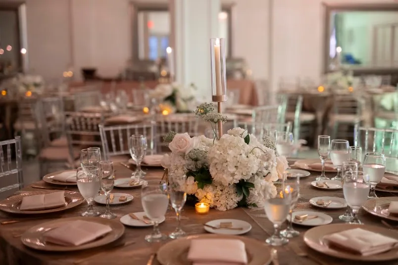 A table set with white flowers, candles and glassware.